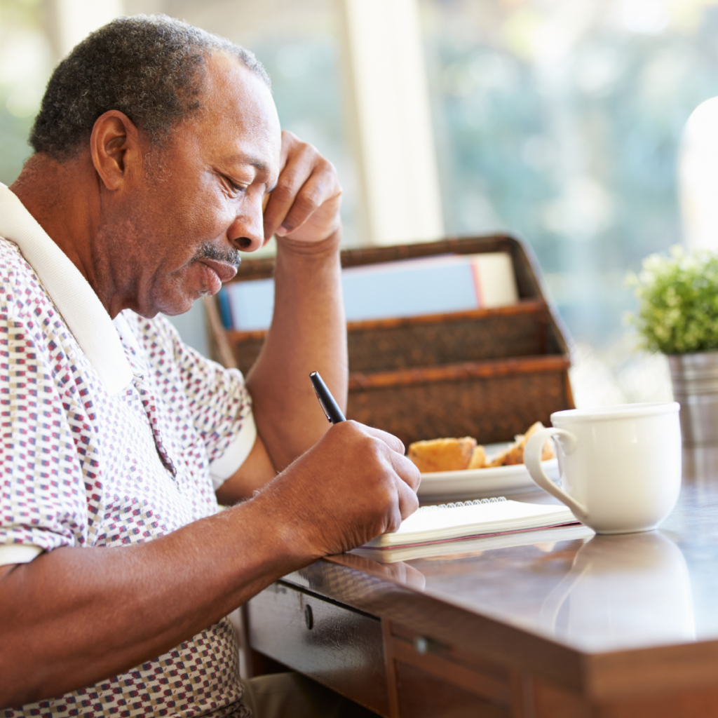 older man at home writing in a notebook