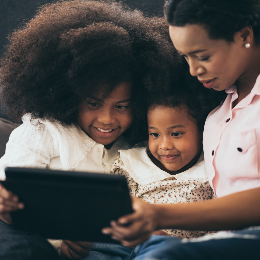 african american mother and daughters seated beside each other using a laptop computer